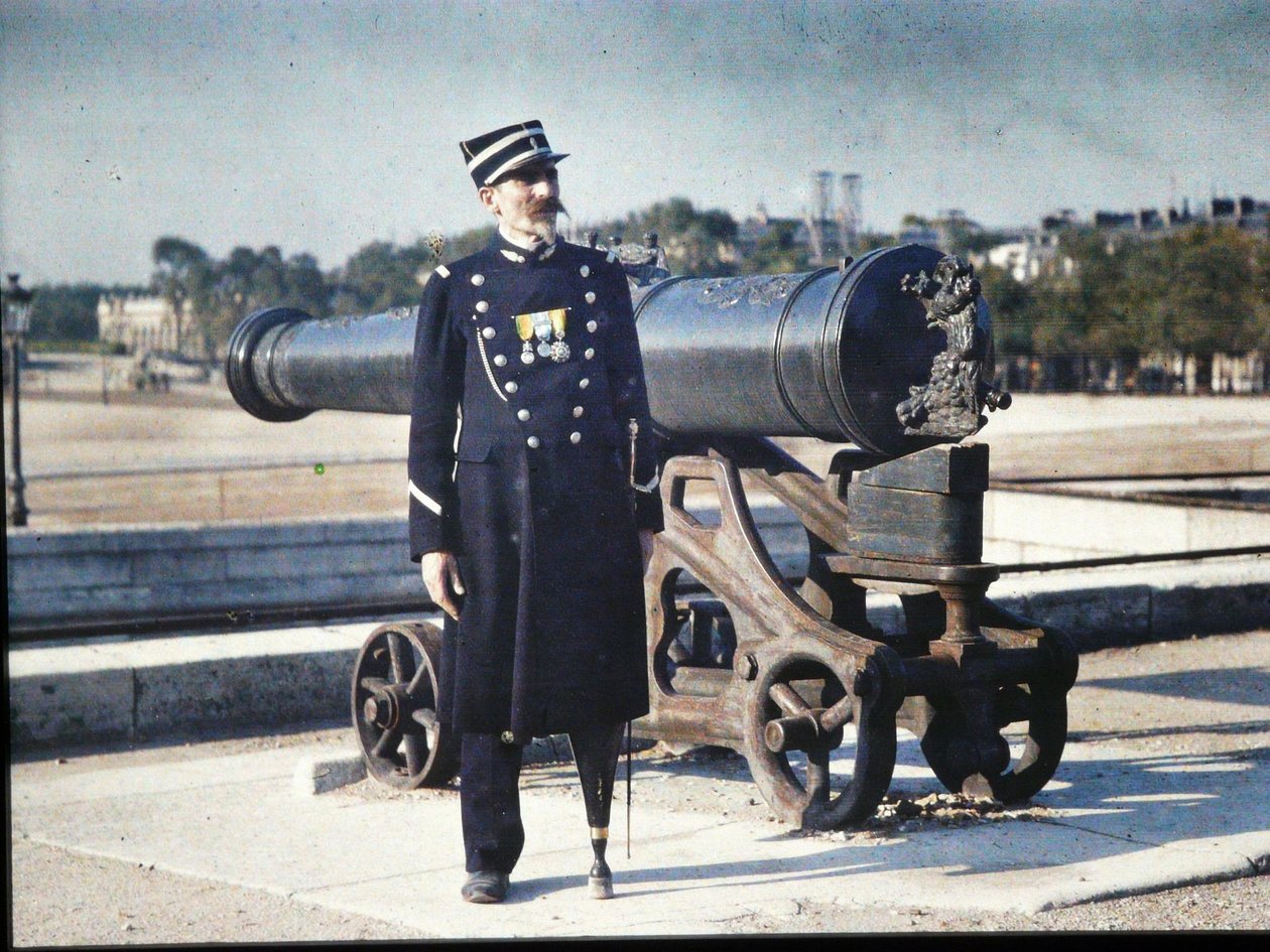 Sotilas univormussa kolmella mitalilla seisoo tykin vieressä Pariisissa, 1918 (autokromi) tekijältä Jules Gervais Courtellemont
