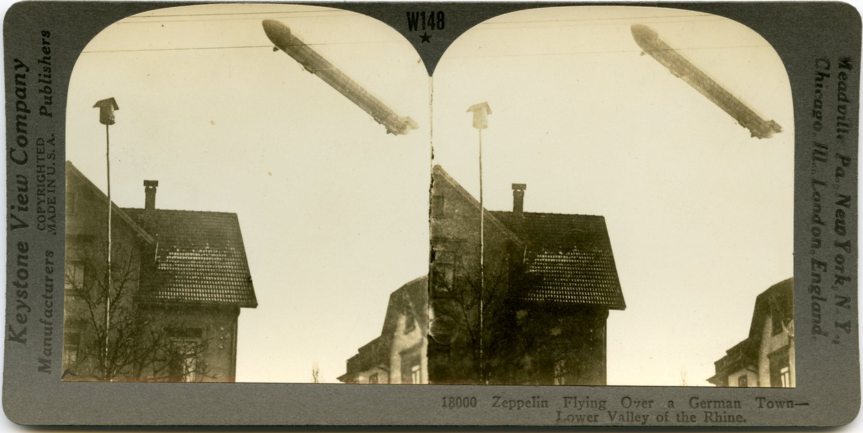 Vaakasuora, seepia -stereokortti, jossa Zeppelin lentää kaupungin kattojen yli. Keystone Stereograph numero 18000. Otsikossa lukee tekijältä Keystone View Company