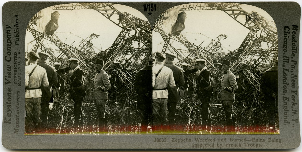 Vaakasuora, seepia -stereokortti, jossa näkyy yhtenäisten miesten ryhmä, joka tutkii zeppelinin hylkyjä. Keystone Stereograph numero 18632. Otsikossa lukee tekijältä Keystone View Company