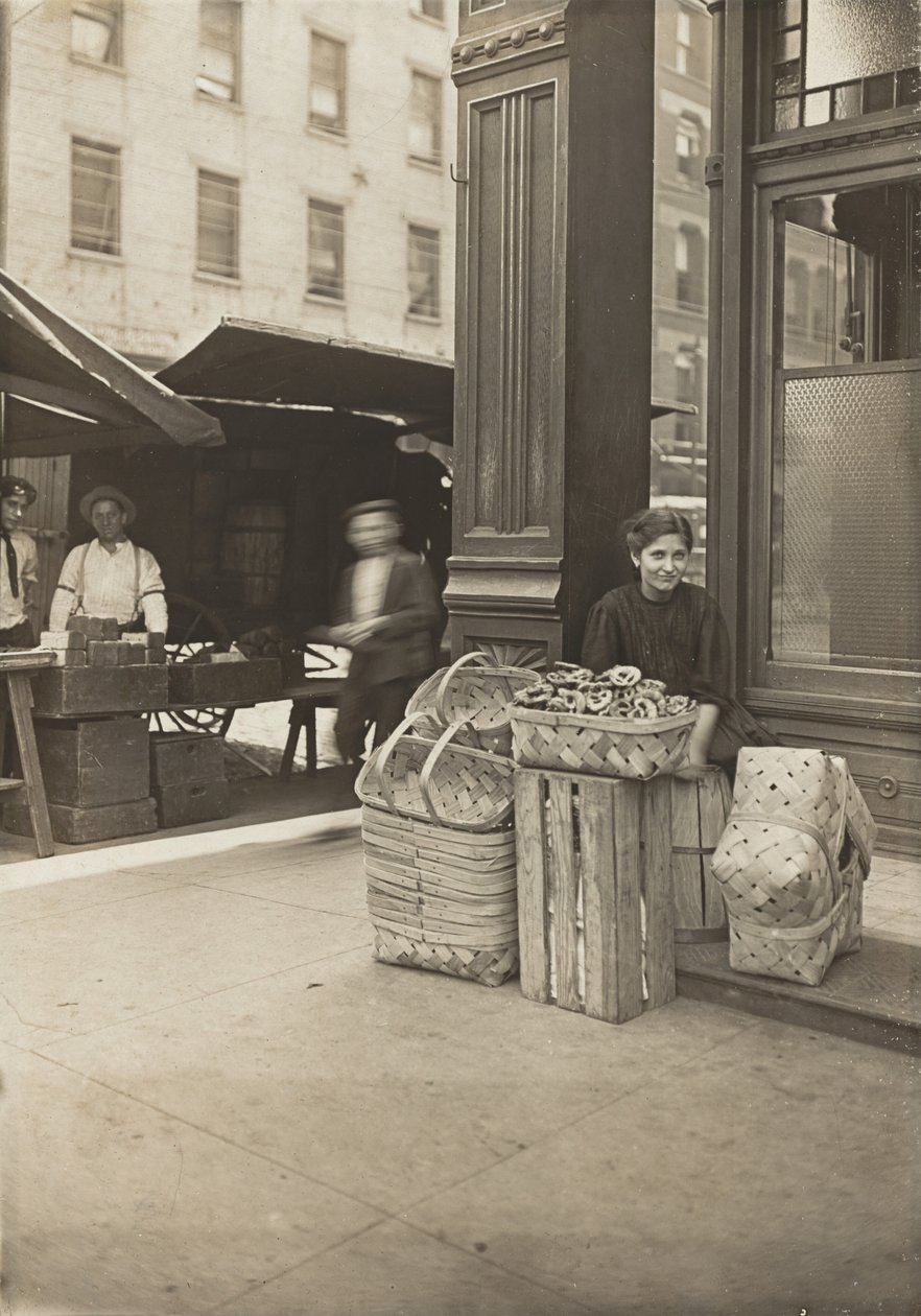 Lena Lochiavo – 11-vuotias, kori- (ja pretzel-)myyjä, Sixth Street Marketissa saluunin sisäänkäynnin edessä, Cincinnati, Ohio tekijältä Lewis Wickes Hine