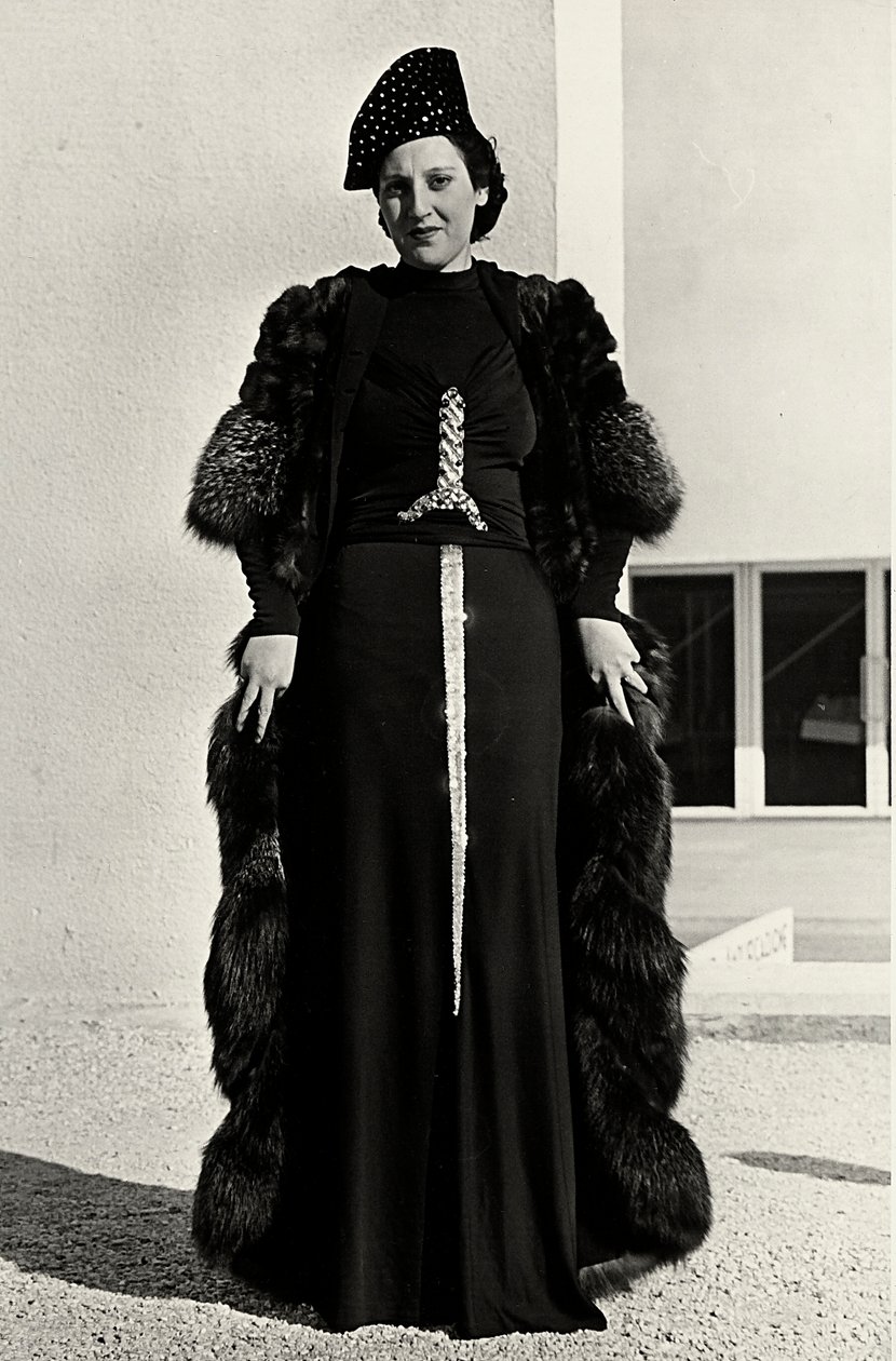 Malli iltapuvussa, jonka on luonut italialainen couture house "Dragoni". Artikkelin fontissa on räikeä, miekan muotoinen paljetekoriste. Hattu ja turkispäällystakki täydentävät kokonaisuuden. (m/w kuva) tekijältä Luis Bogino