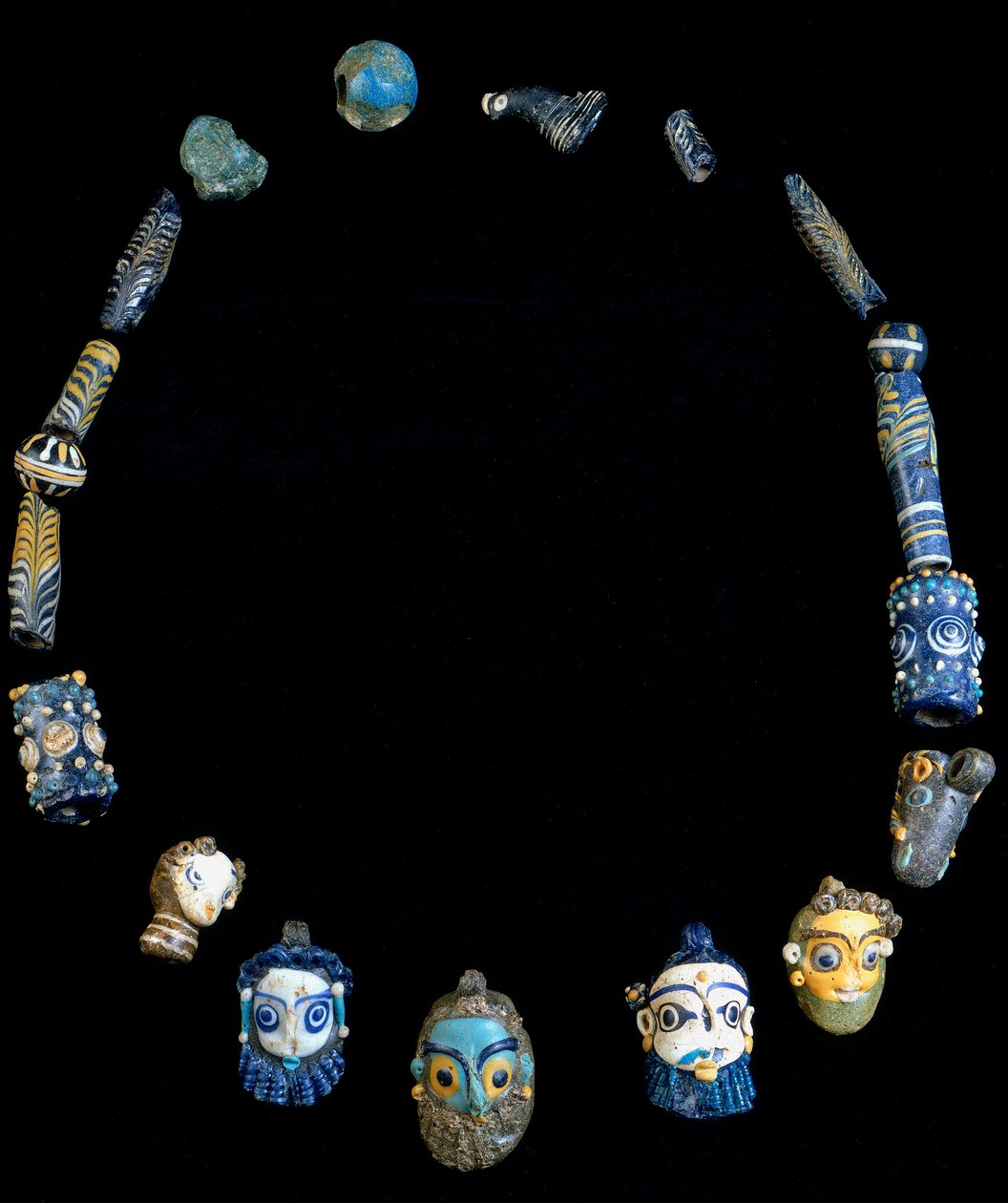 Lasitahnasta valmistettu kaulakoru riipuksilla, jotka kuvaavat parrakkaita päitä, alun perin Olbiasta, nyt säilytetty Cagliarin kansallisessa arkeologisessa museossa tekijältä Phoenician Phoenician