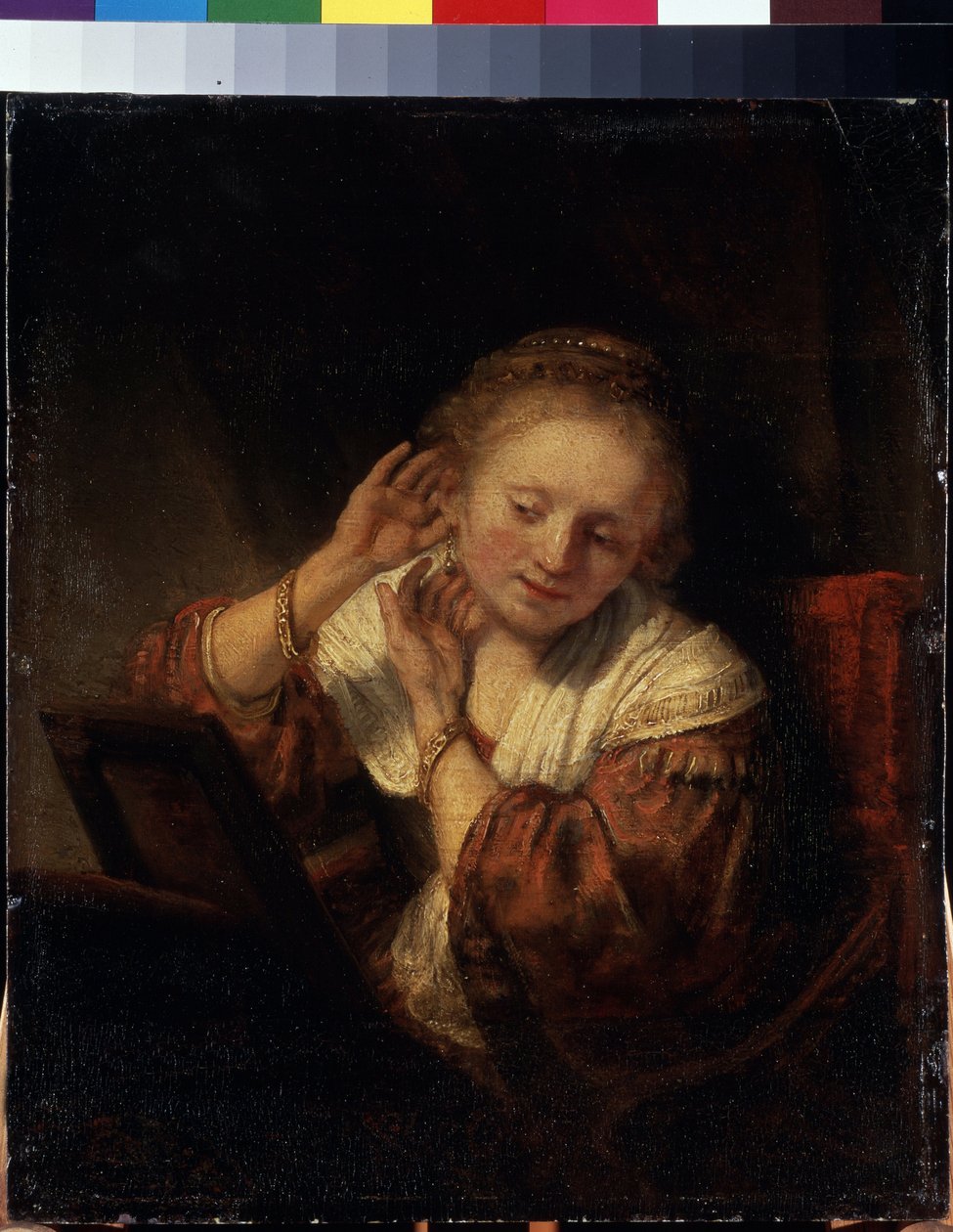 Nuori nainen yrittää korvakoruja. Nuori nainen kokeilee korvakoruja. Harmenszoon van Rijnin maalaus, joka tunnetaan nimellä Rembrandt (1606-1669) tekijältä Rembrandt Harmensz. van Rijn