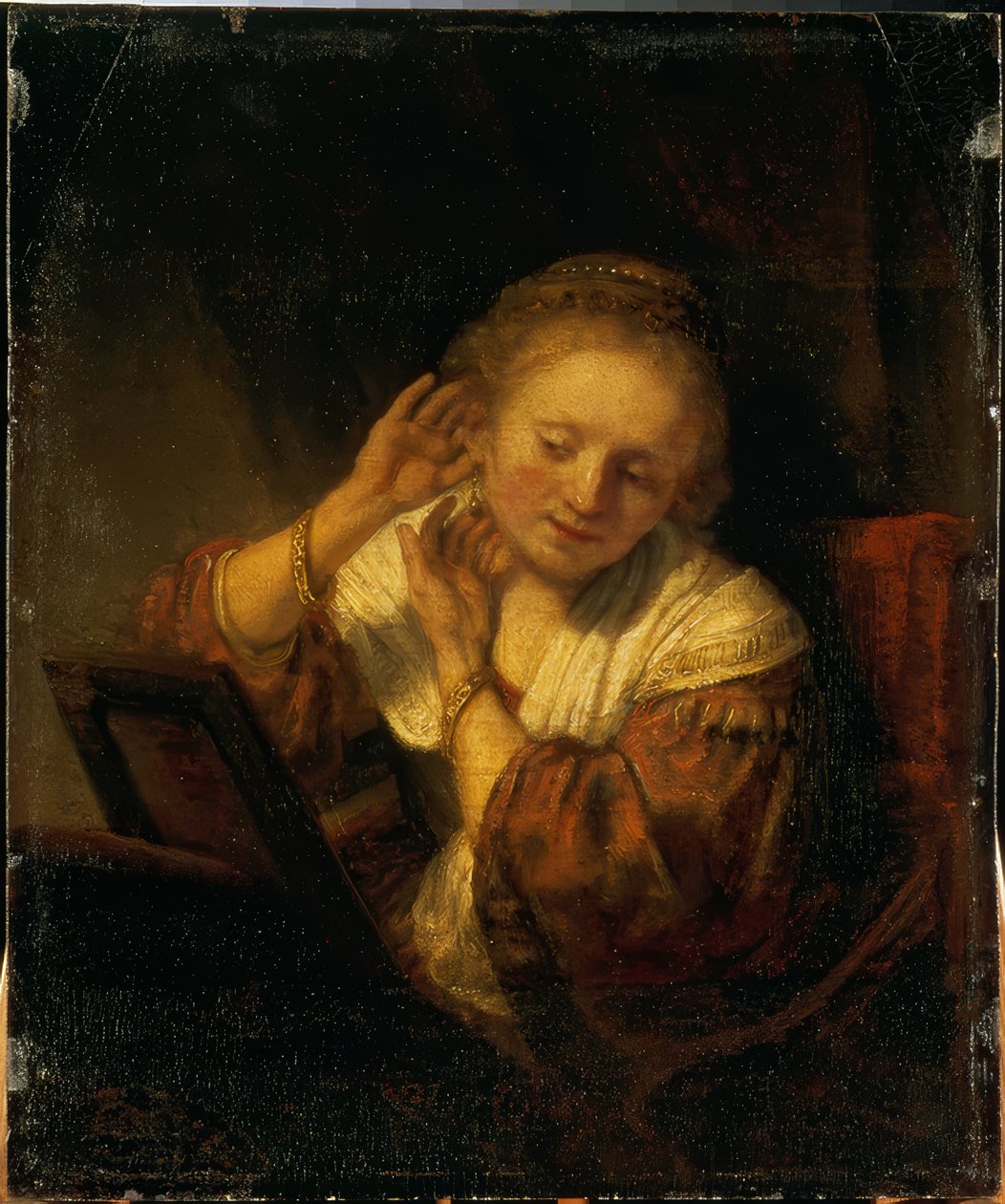 Junge Frau, sich mit Ohrringen schmückend tekijältä Rembrandt van Rijn