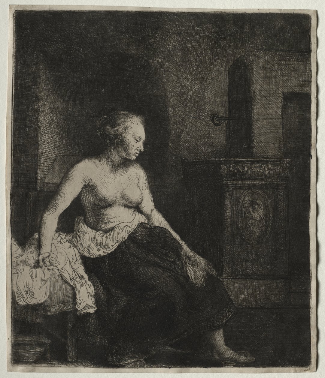Nainen istuu puolipukeutuneena lieden vieressä tekijältä Rembrandt van Rijn