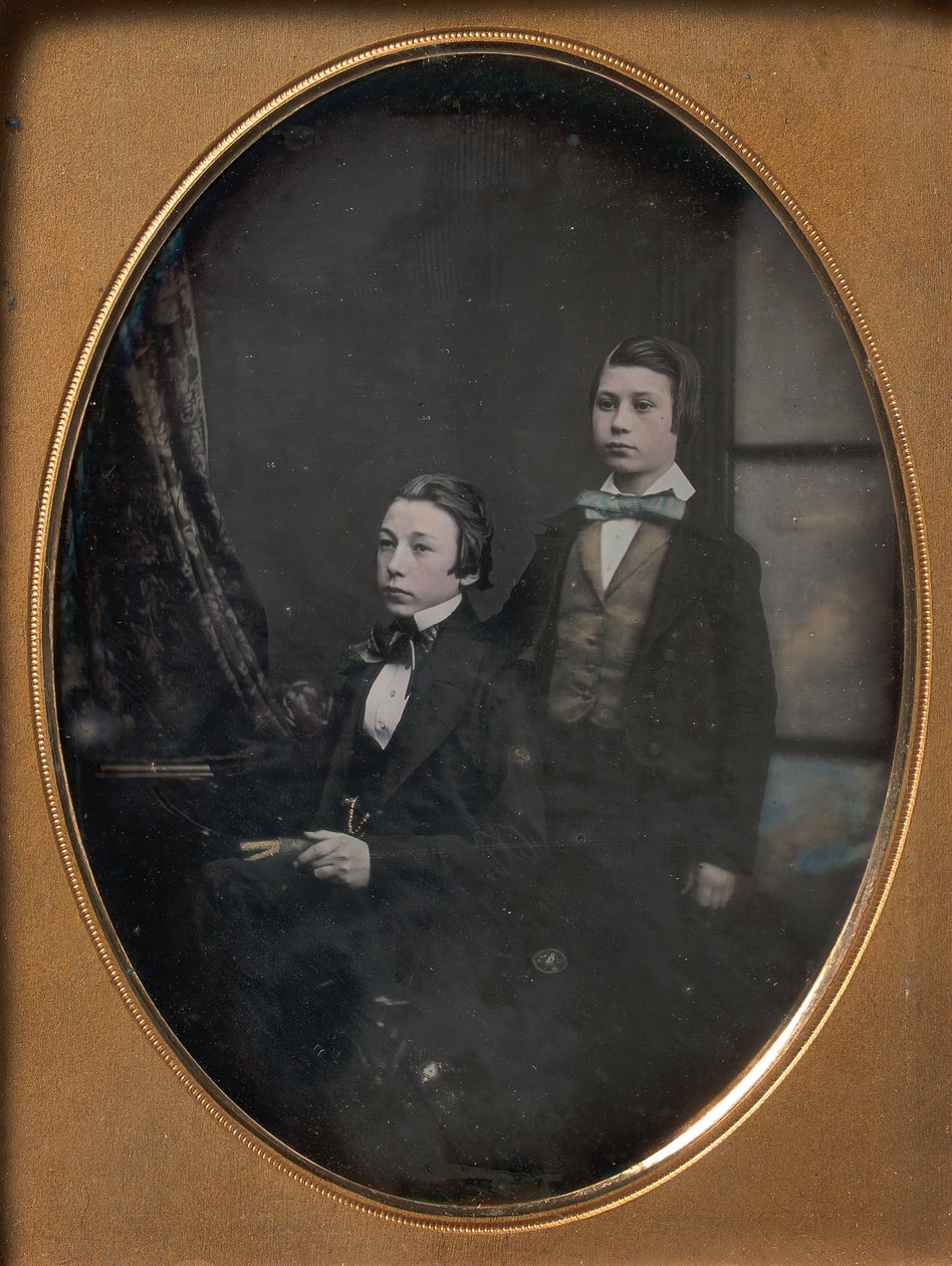 Kaksi nuorta miestä rusetissa, yksi istuu kirjaa kädessään, toinen seisomassa, 1850-luku. tekijältä Robert Boning