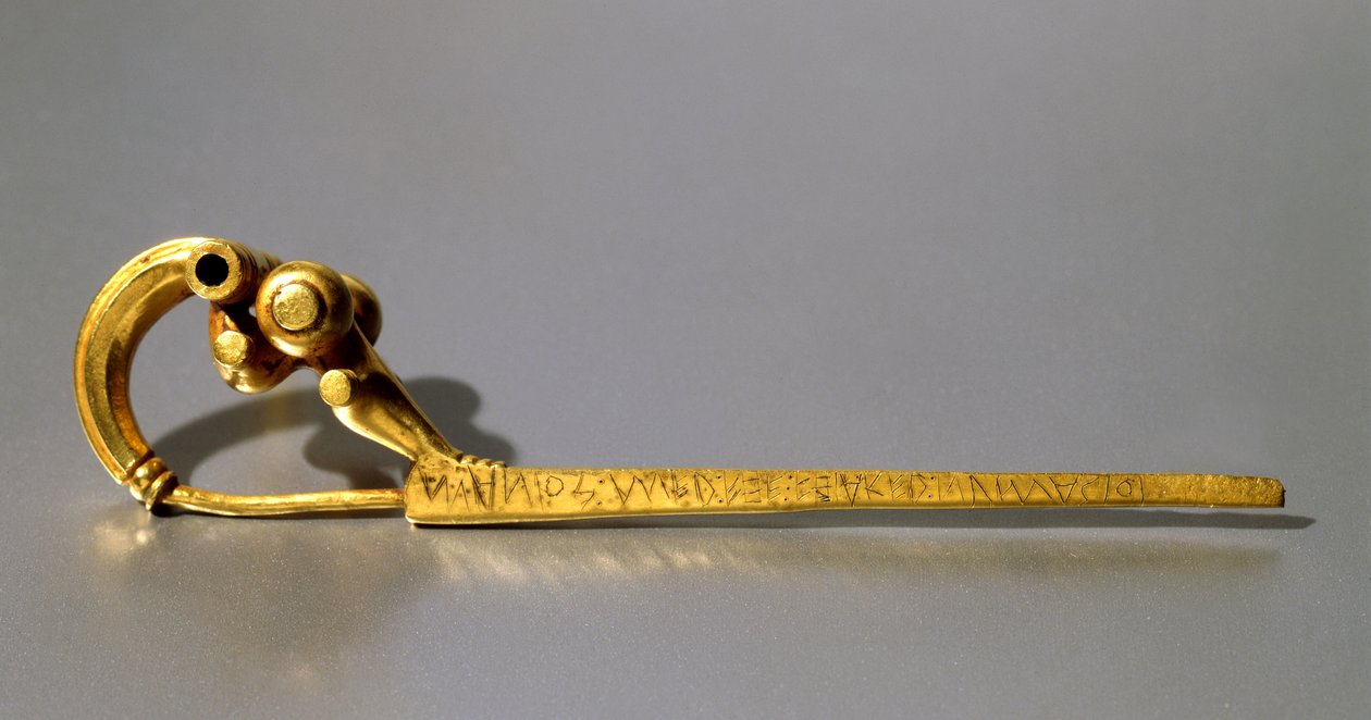 Fibula, Palestrinasta, jossa merkintä "Manios" (kulta) tekijältä Roman