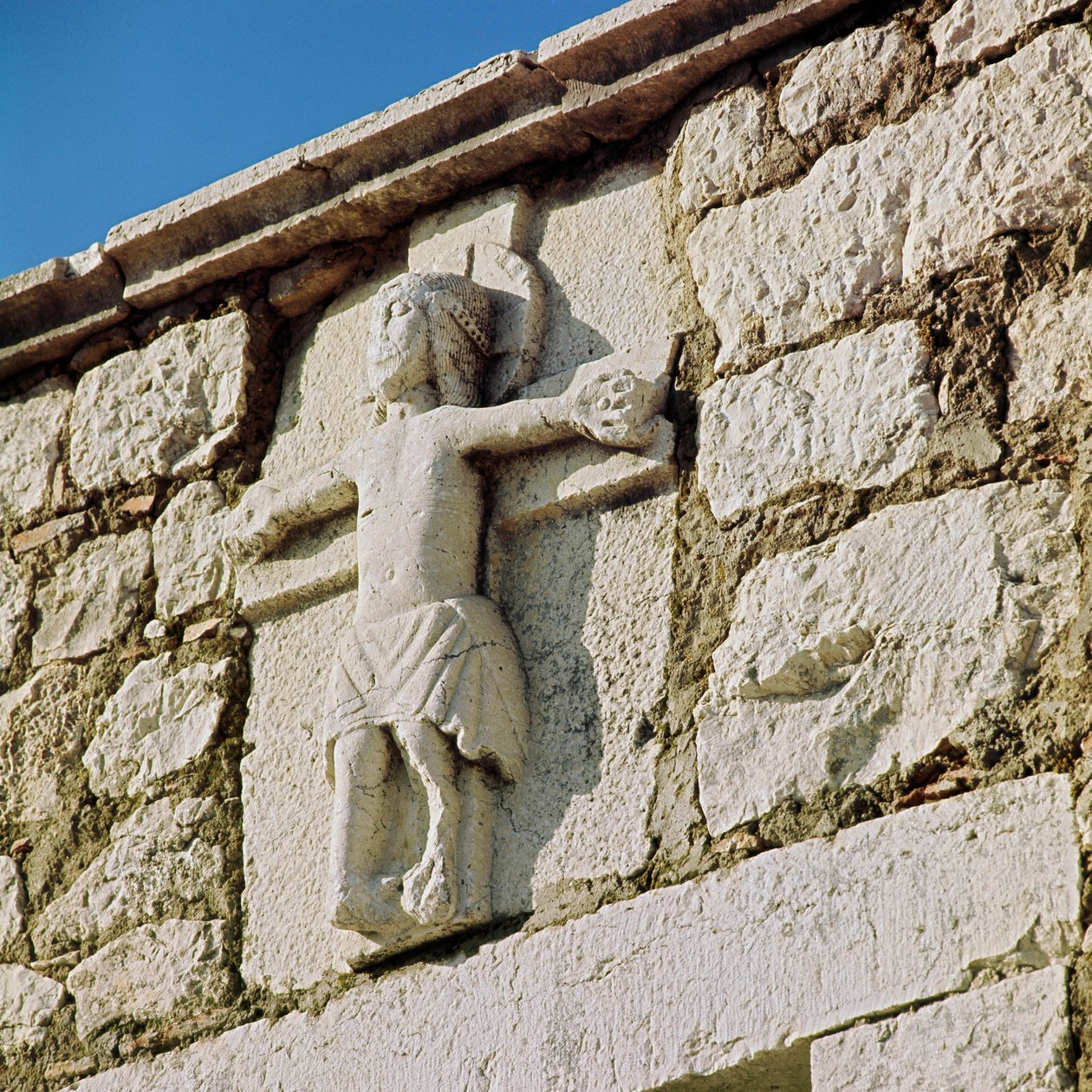 Kristus ristiinnaulitsee kiviveistoksen 1200-luvulta. San Bartolomeon romaanisen kirkon portaali, Campobasso Italia tekijältä Romanesque