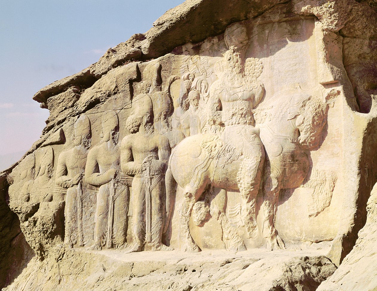 Kalliorelief, joka kuvaa Shapur I:tä (241–272 jKr) ja hänen perhettään pitämään hatussaan heraldisia tunnuksia (kuva) tekijältä Sasanian
