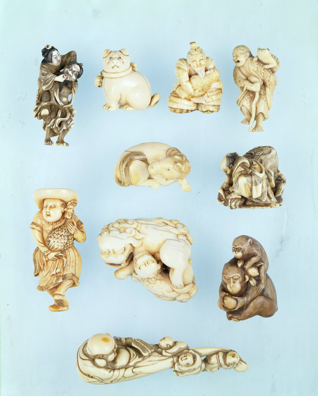 Valikoima netsuke: Ikkuha Sennin kantaa Benaresin porttoa; istuva pentu; Abe no Yasuneri pitelee vauvaa; Gamma Sennin; makaava hevonen; soturi alistamassa karanneen härän; seisova hollantilainen, jolla on pitkähäntäinen kukko; istuva apina, jolla on persik tekijältä Japanese School