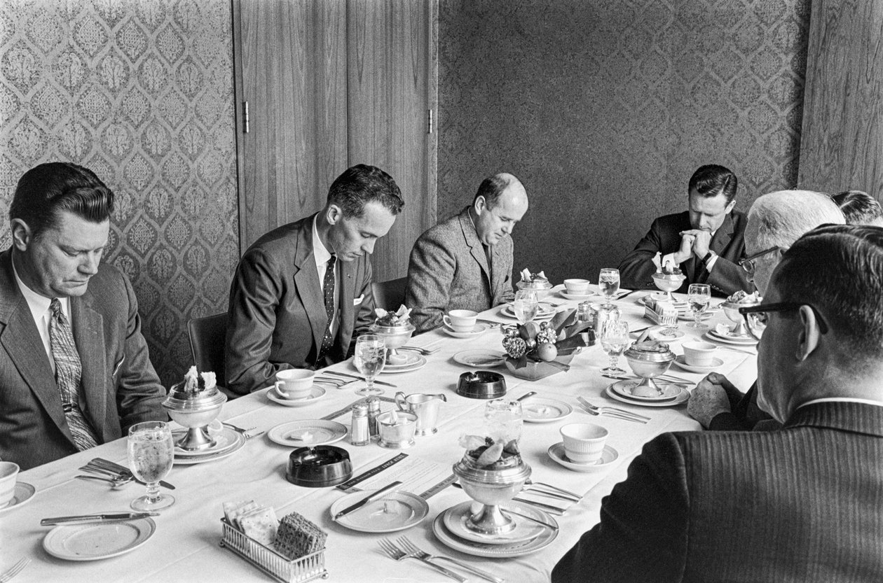 Liikemiehet rukoilevat ennen lounaan syömistä kirkon varainhankintakokouksessa. tekijältä Ted Spiegel