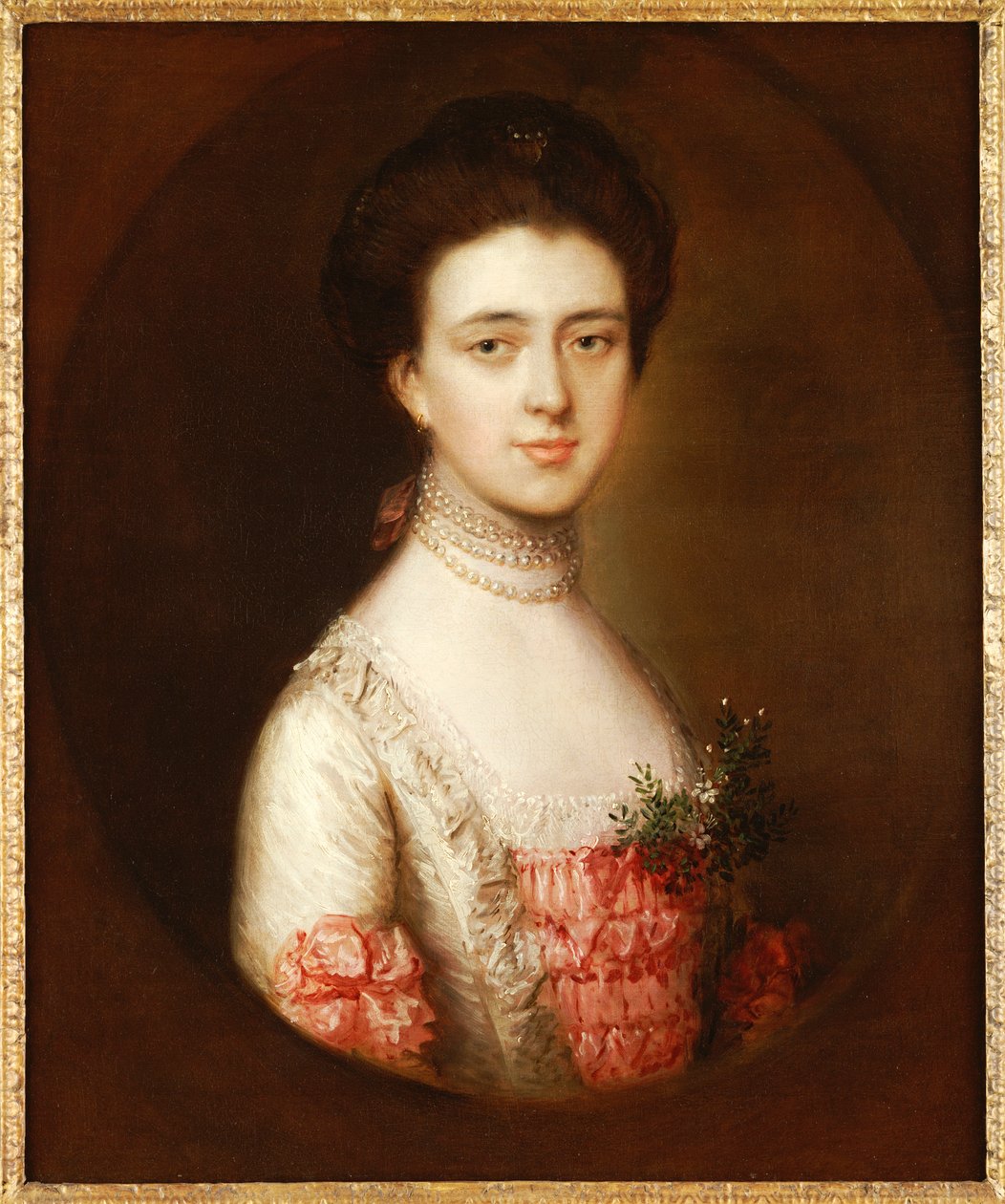 Naisen muotokuva, rinnan mittainen, vaaleanpunaisessa ja valkoisessa mekossa, jossa on pitsiä ja helmikaulakoru tekijältä Thomas Gainsborough
