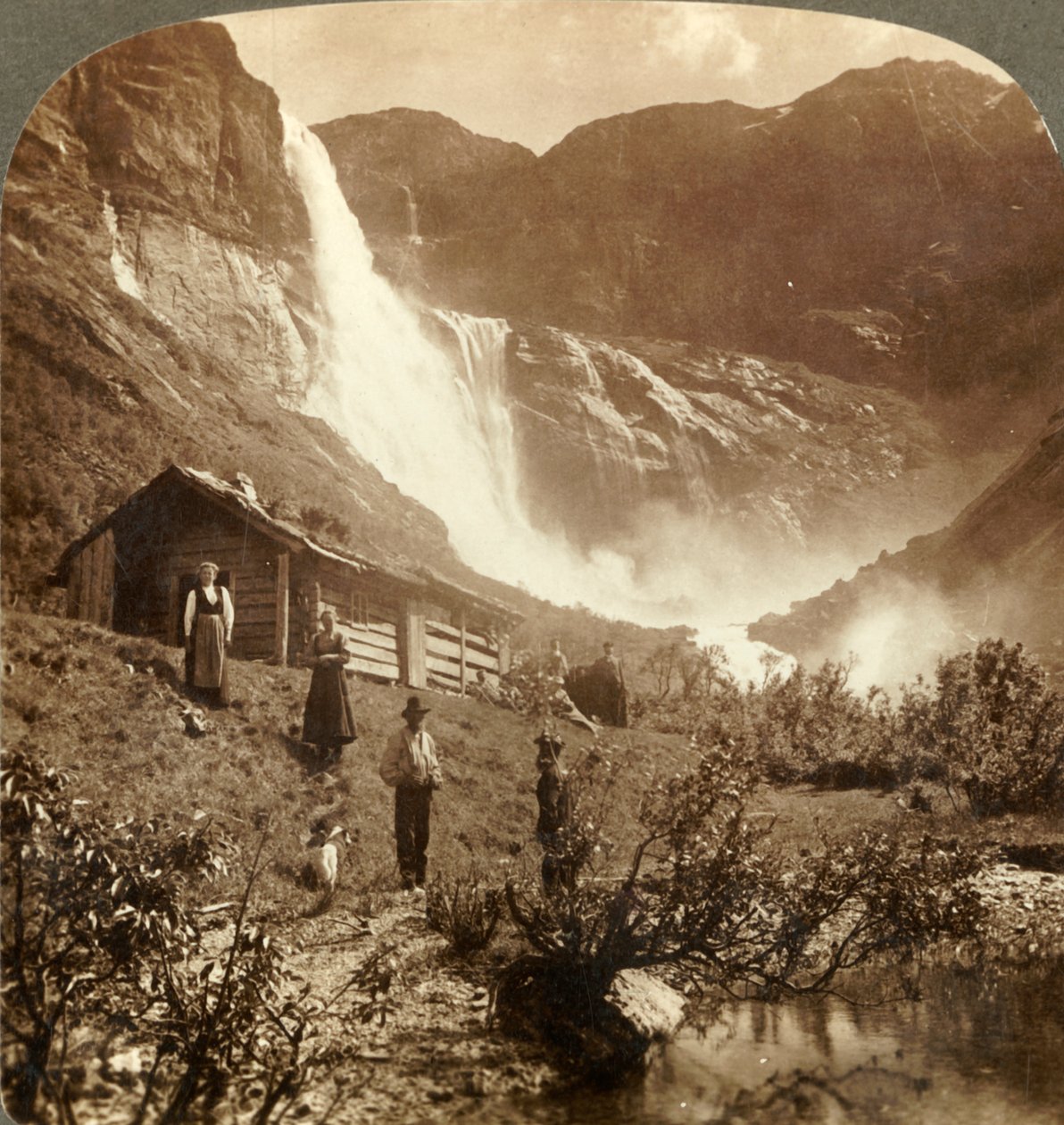 Nöyrä vuoristotalo kallioiden juurella, jossa Skiaeggedals Falls hyppää 525 jalkaa, Norja, 1905. tekijältä Unbekannt