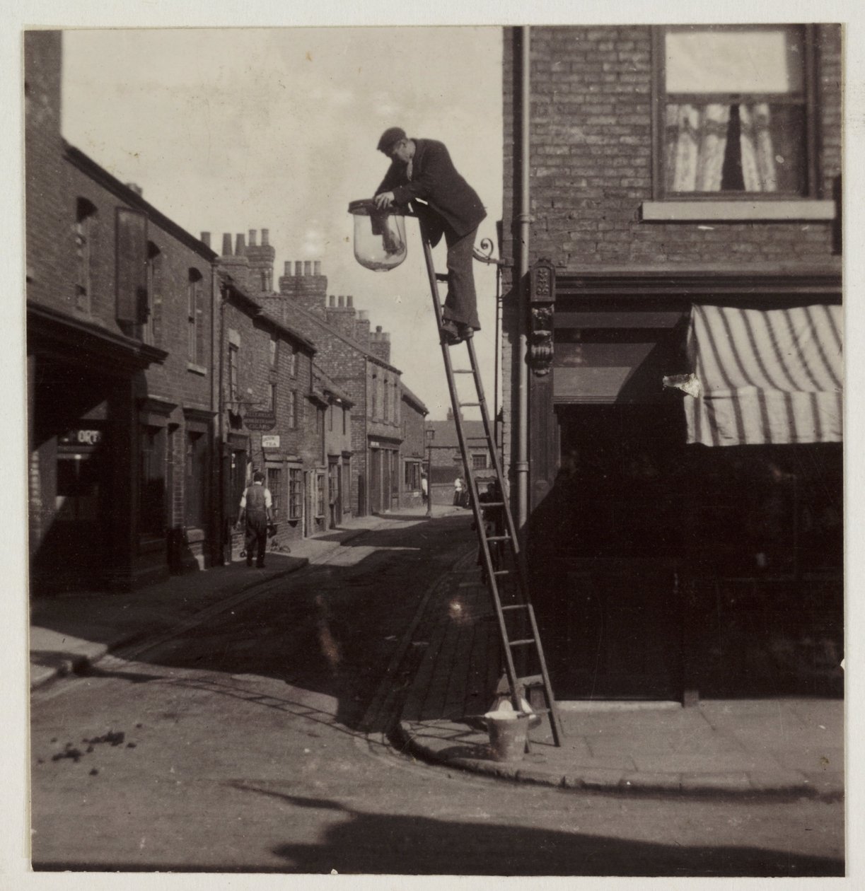 Mies puhdistamassa kaasukatuvaloa, n. 1905 tekijältä Unbekannt