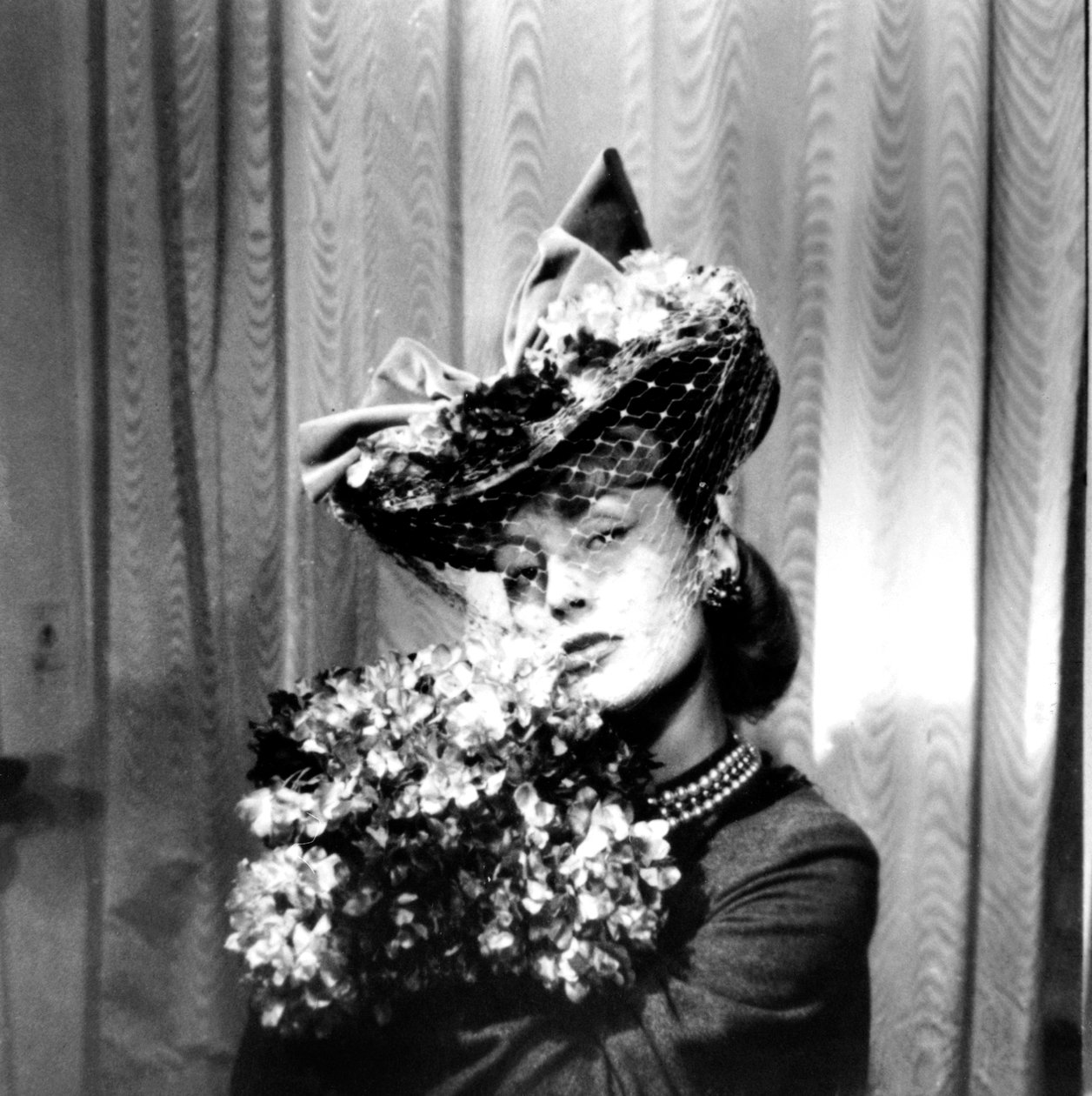 Nainen, jolla on hunnulla varustettu hattu, kädessään kukkakimppu, Pariisi, 1943 tekijältä Unbekannt