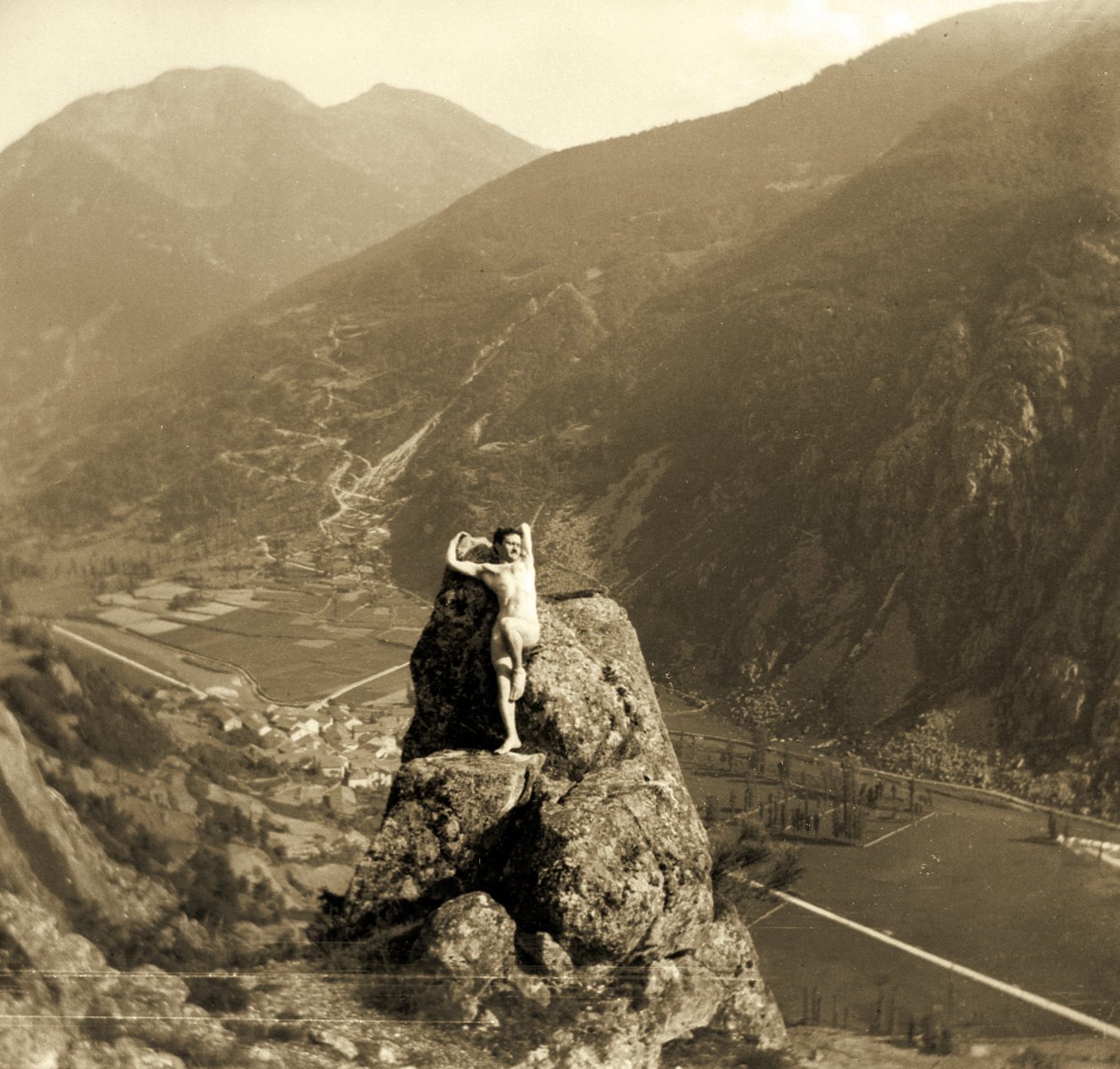 Mies alaston poseeraa kalliolla vuoristoisessa laaksossa, n. 1910 tekijältä Unbekannt Unbekannt
