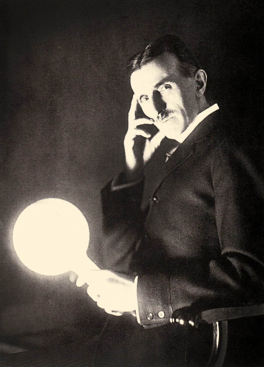 Muotokuva Nikola Teslasta pitelee hehkulamppua, joka valaisee Tesla-kelan sähkömagneettisen kentän, 1899 tekijältä Unbekannt Unbekannt