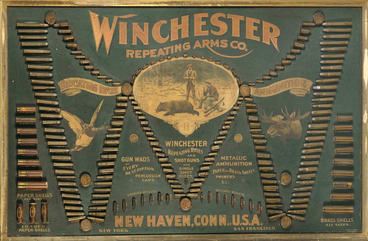 Winchester Cartridge -näyttötaulu, jossa on kattava valikoima metalli-, messinki- ja paperikoteloisia kivääri- ja haulikapurukkeja, jotka on järjestetty laajennetun "W"-kirjaimen muotoon. tekijältä Unbekannt