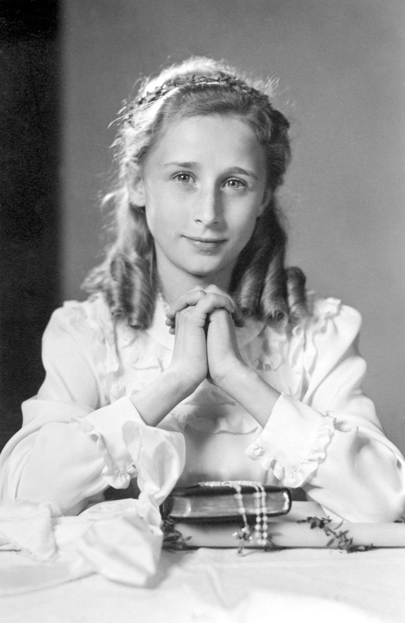 Kristitty tyttö, jolla on kädet rukousasennossa Raamatun, rukouksen ja kynttilän kanssa (kuva ehtoollisesta). Valokuvaus noin 1932 tekijältä Unbekannt
