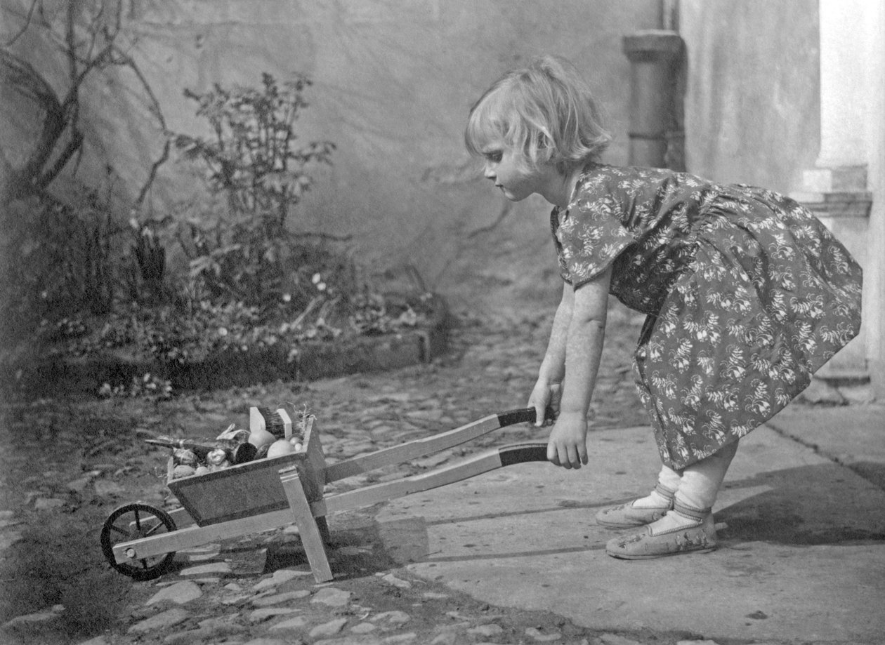 Pikkutyttö leikkii kottikärryillä. Valokuvaus noin 1931 tekijältä Unbekannt
