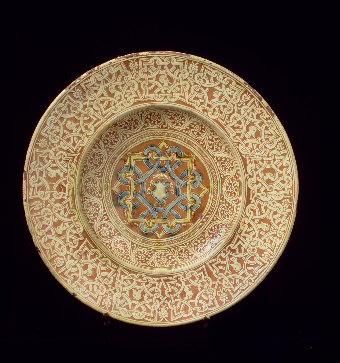 Maiolica-levy koristeltu monimutkaisella toistuvalla solmukuvioinnilla, jotka kehystävät profiilipäät reunassa ja kilpi keskikilvessä, italialainen, valmistettu Toscanassa tekijältä Unknown