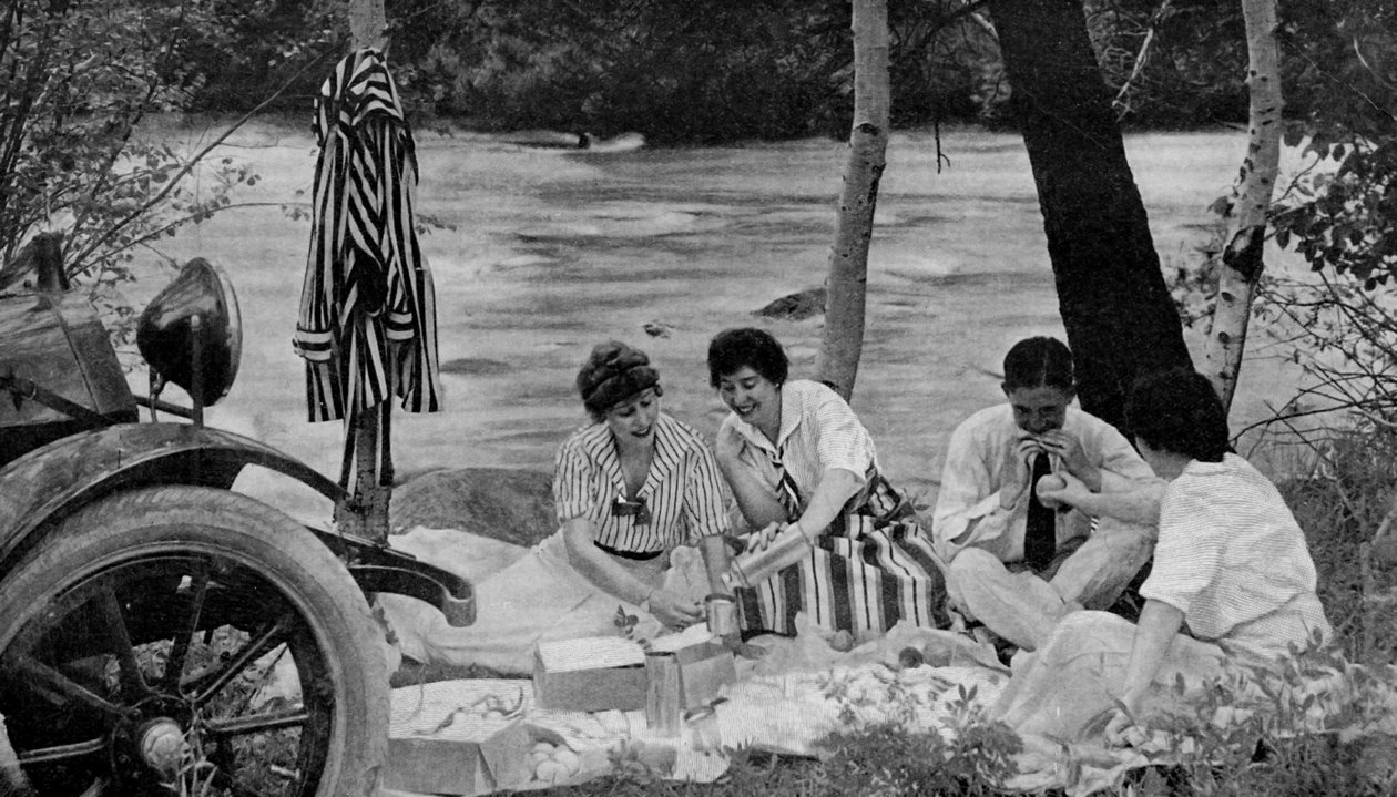 Pohjois-Amerikka. Piknik-bileet hyökkäävät lounaskoriin moottorimatkalla Ozark-vuorille. 1920 tekijältä Unbekannt