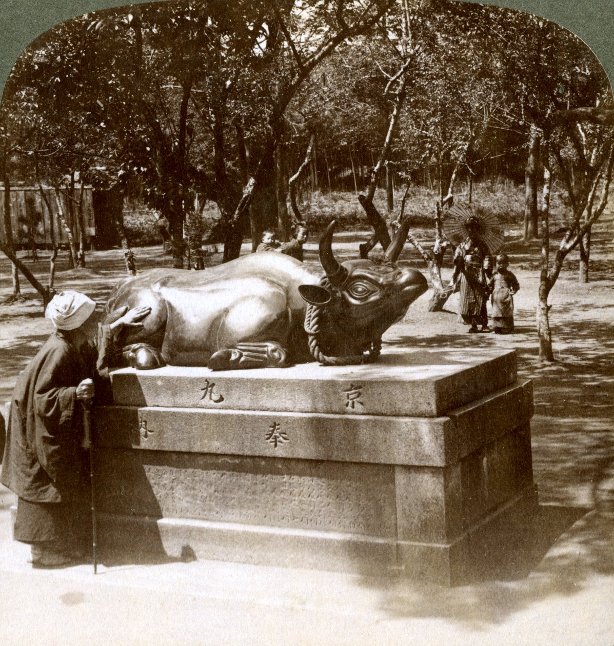 Harras nainen silitti pronssista härkää parantaakseen reumaa, Kitano Tenjinin temppeli, Kioto, Japani, 1904 tekijältä Underwood and Underwood