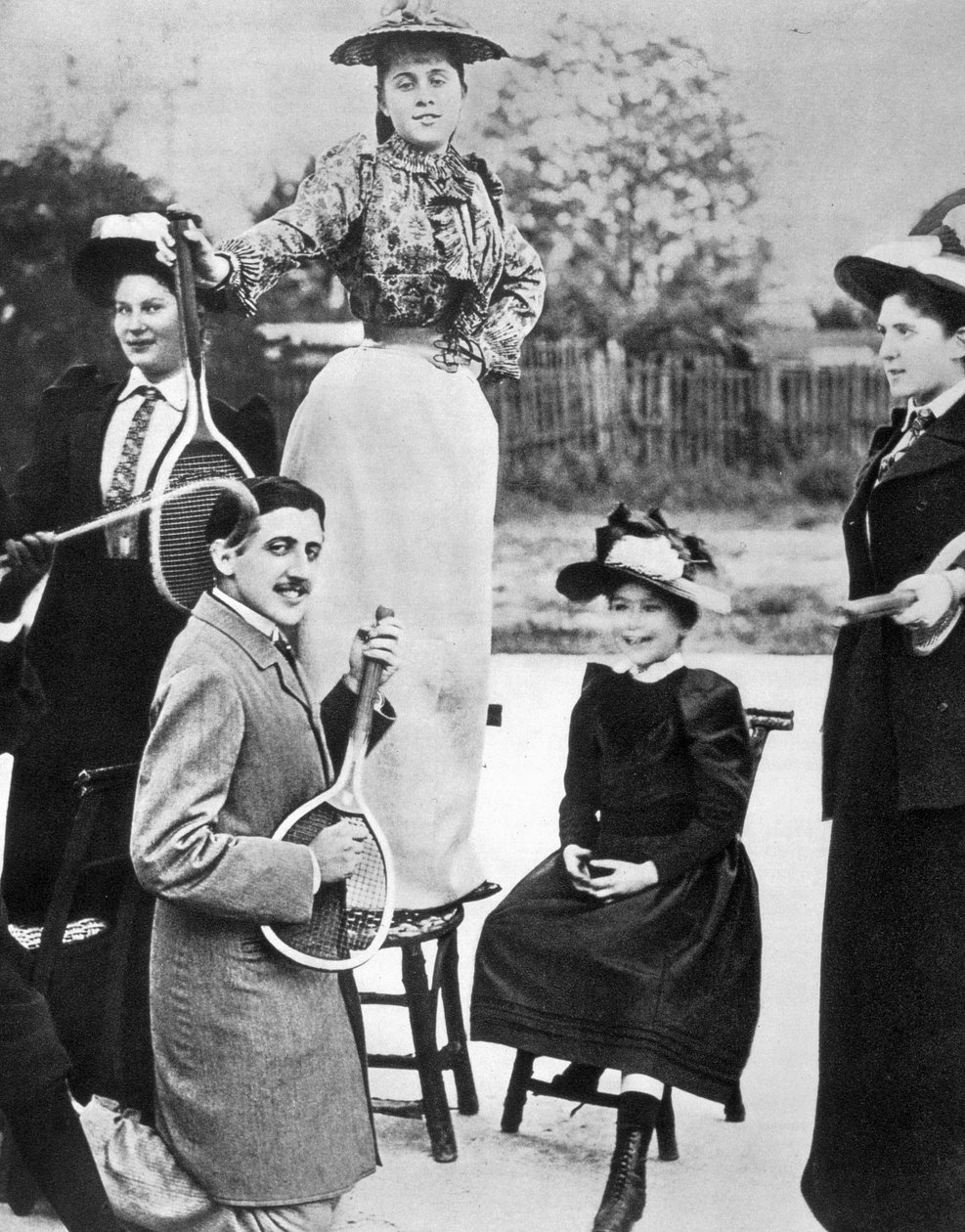 Marcel Proust nuorten naisten joukossa soittamassa kitaraa tennismailalla Bineau Boulevardilla Pariisissa tekijältä Unknown photographer