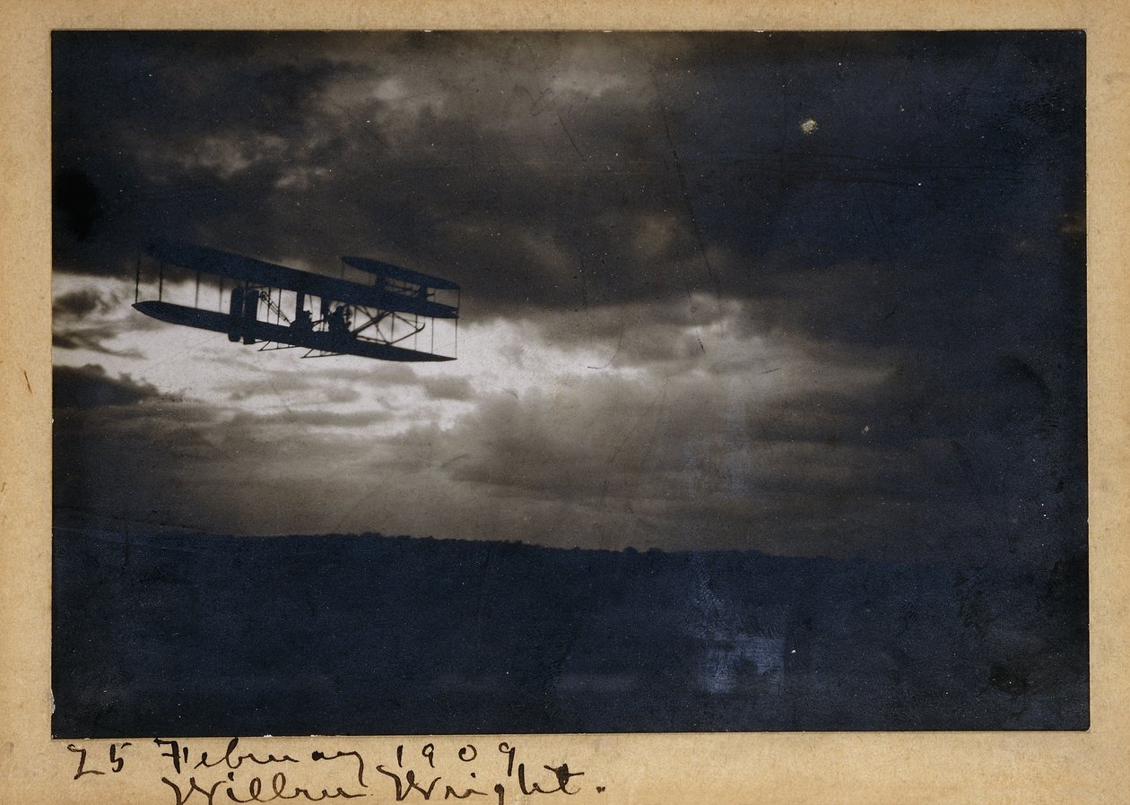Wilbur Wright lennossa, omakätinen signeeraus "Wilbur Wright" ja päivämäärä "25. helmikuuta 1909", noin 1909 (gelatiinihopeatuloste, kiinnitystelineellä, muste). tekijältä Unknown photographer