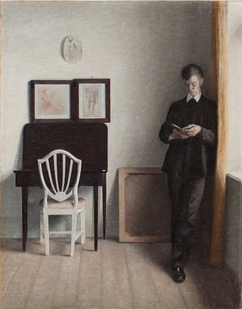 Sisustus, jossa nuori mies lukee tekijältä Vilhelm Hammershoi