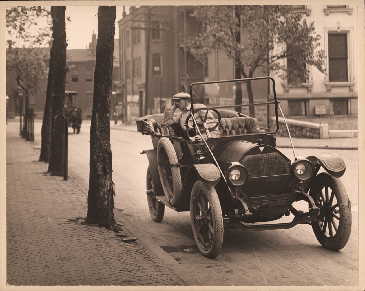 Mies istuu autossa tuntemattomalla kadulla. tekijältä William G. Swekosky
