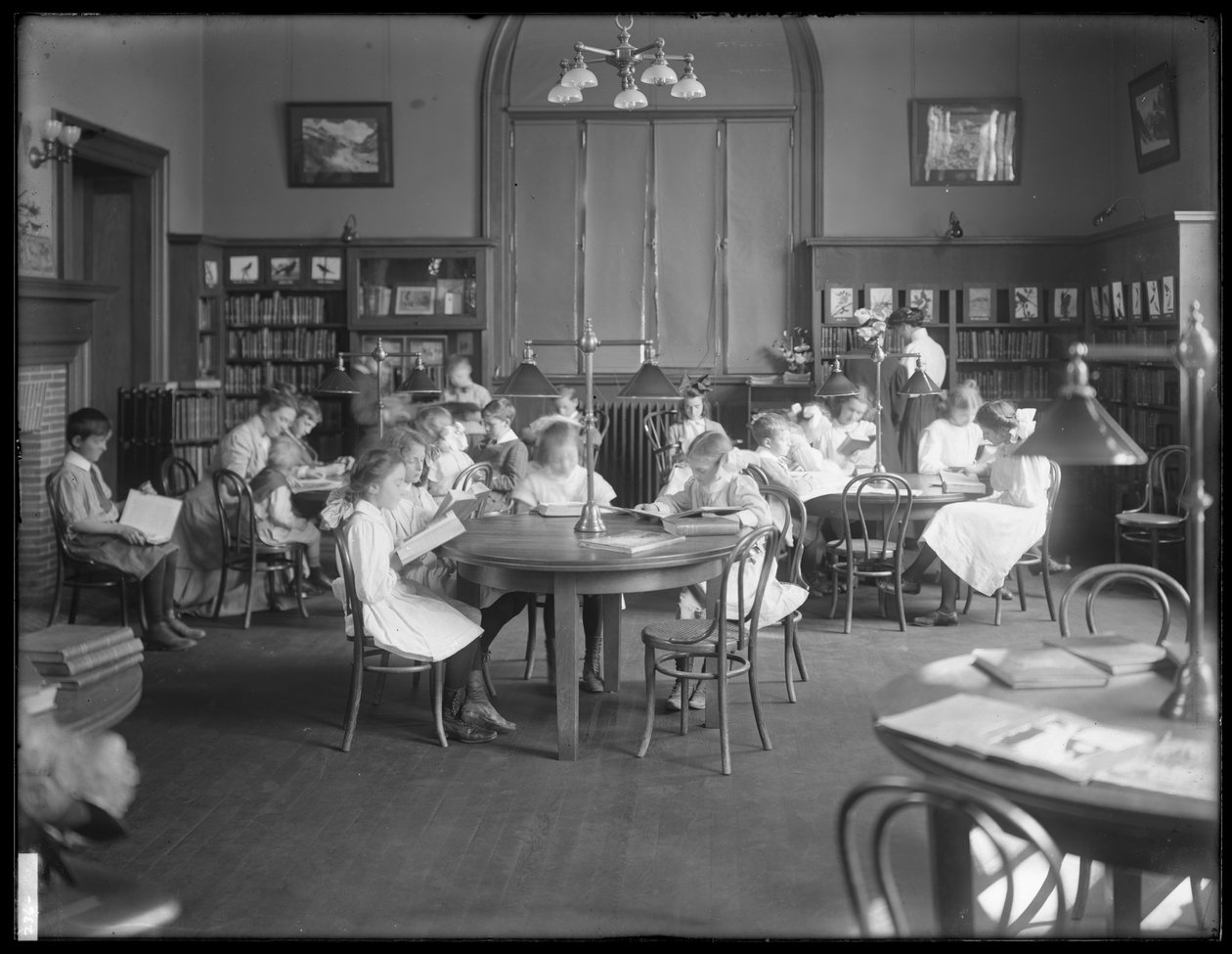 Lapset lukevat Queens Borough Public Libraryn tunnistamattoman haaran lukusalissa, n. 1910 tekijältä William Davis Hassler