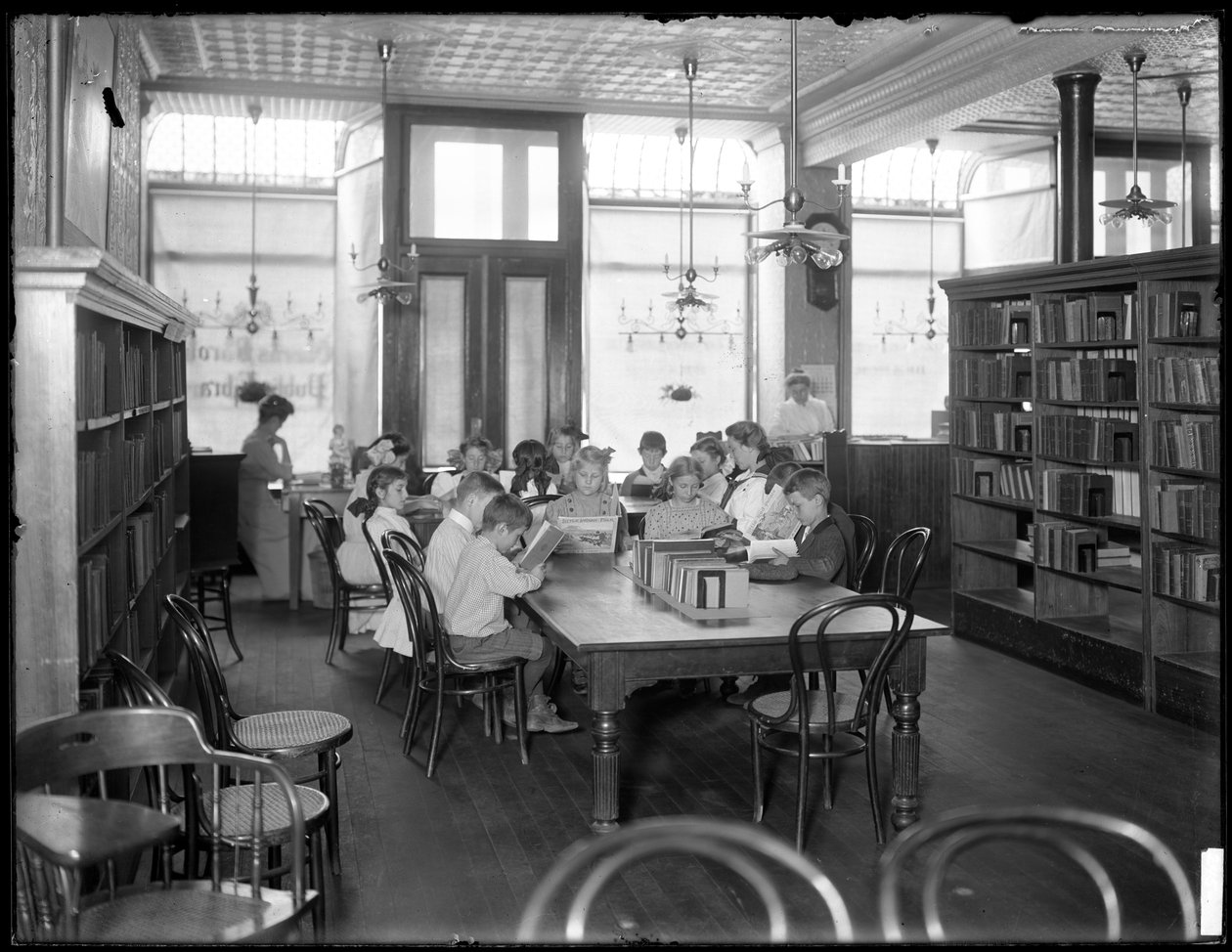 Lapset lukevat Queens Borough Public Libraryn tunnistamattoman haaran lukusalissa, n. 1910 tekijältä William Davis Hassler