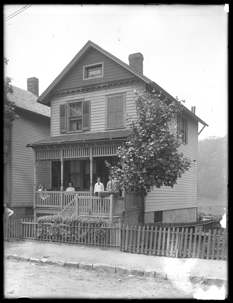 Neljä lasta poseeraa joen tai järven rannalla sijaitsevan talon kuistilla, Inwood, New York, noin 1910. tekijältä William Davis Hassler