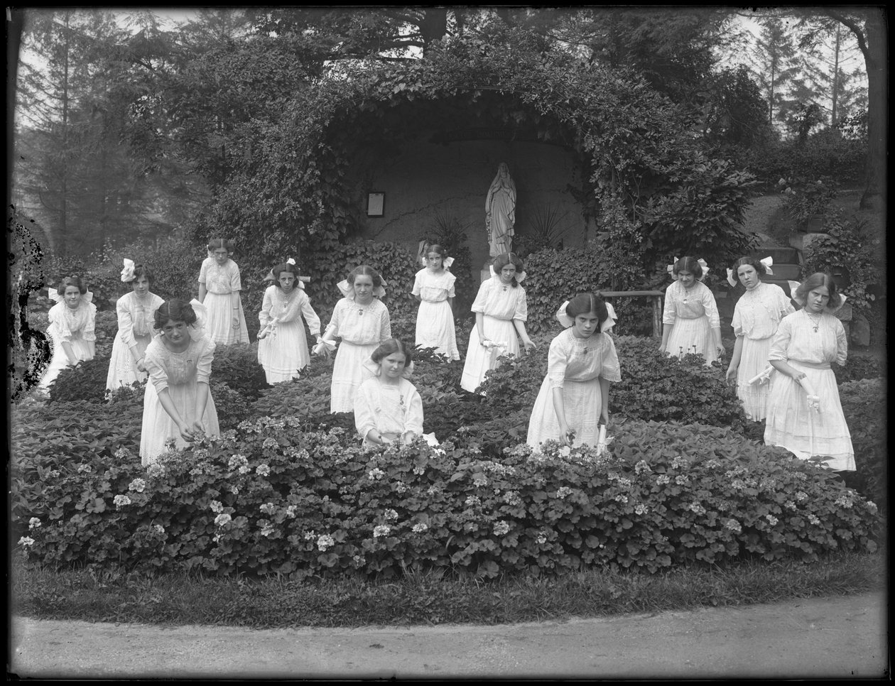 Ylioppilasluokka roomalaiskatolisesta orpojen turvapaikasta kukkapuutarhassa, Neitsyt Marian luolan edessä, 1912 bw kuva tekijältä William Davis Hassler