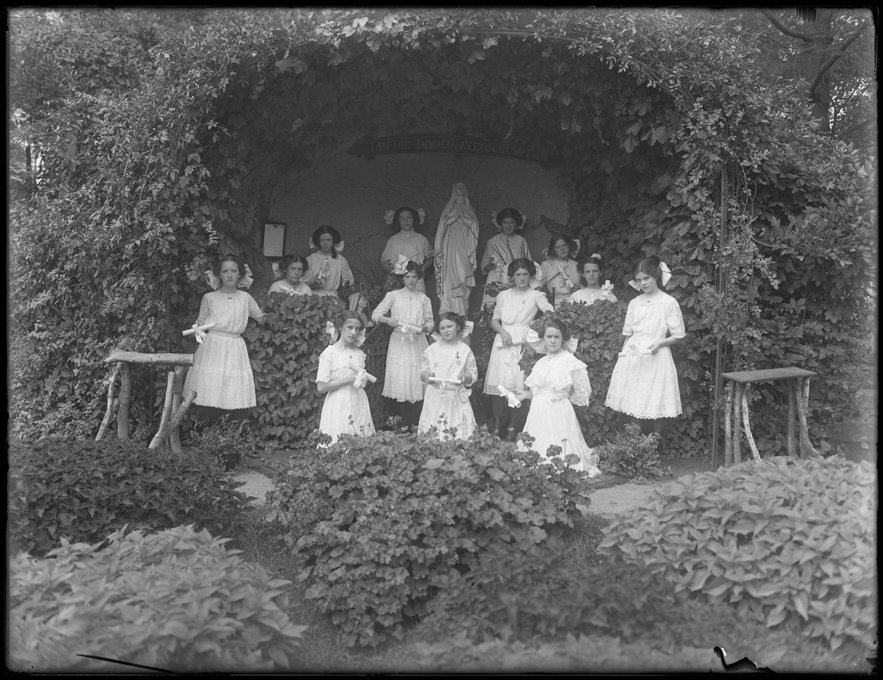 Roomalaiskatolisen orpojen turvapaikan valmistuvat tytöt poseerasivat luolan edessä tutkintotodistusineen, 1912 tekijältä William Davis Hassler