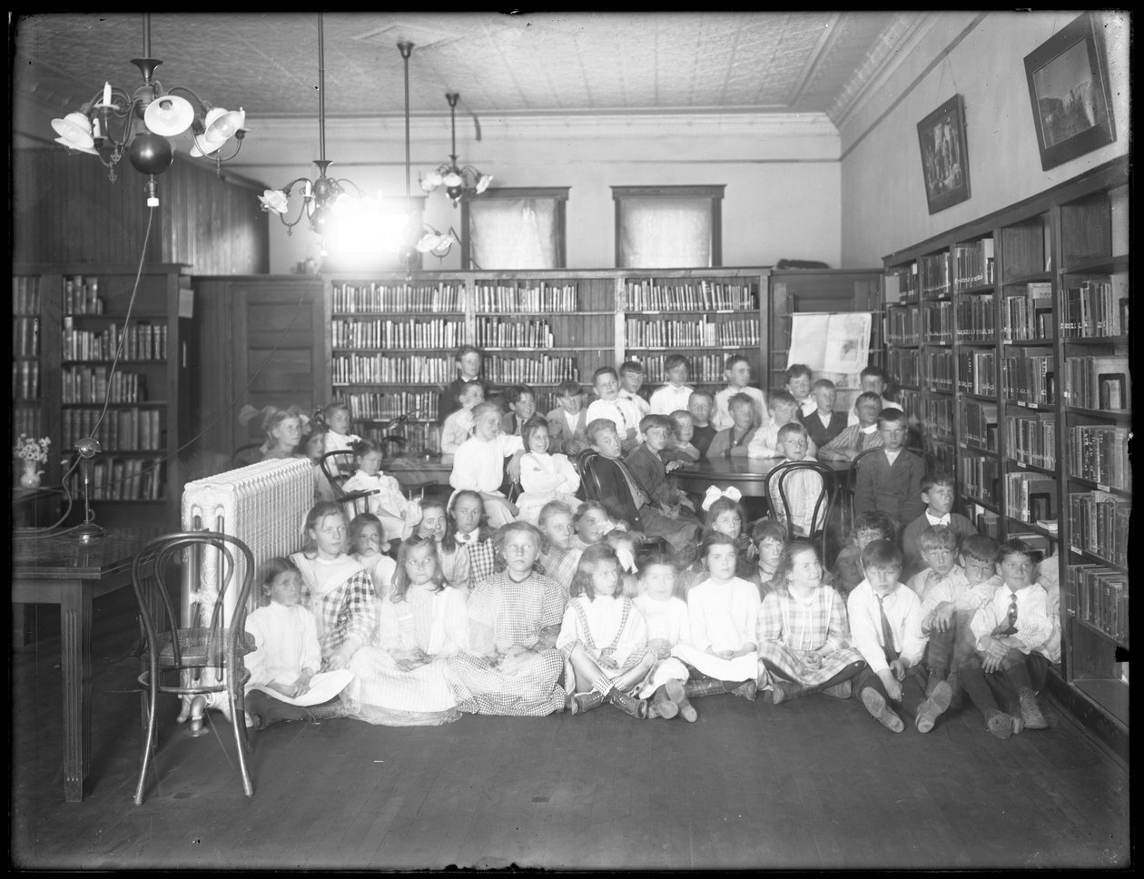 Ryhmäkuva lapsista Queens Borough Public Libraryn tunnistamattoman haaran lukusalissa, n. 1910 tekijältä William Davis Hassler
