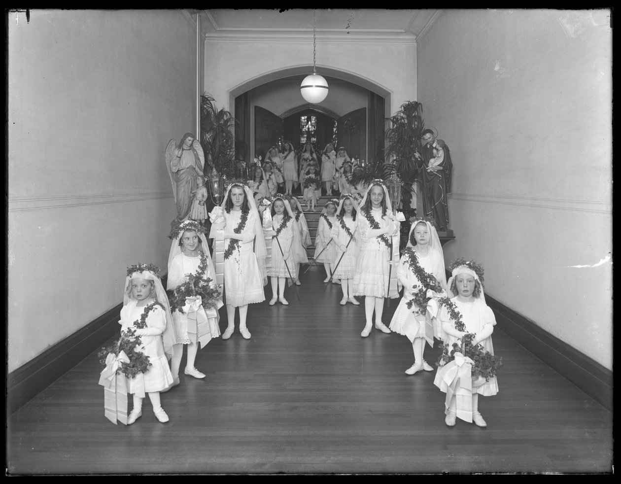 Pienet tytöt roomalaiskatolisessa orpojen turvapaikassa, Kingsbridge, Bronx, palaavat kappelista valkoisissa mekoissa, seppeleillä ja seppeleillä, 20. lokakuuta 1914 tekijältä William Davis Hassler