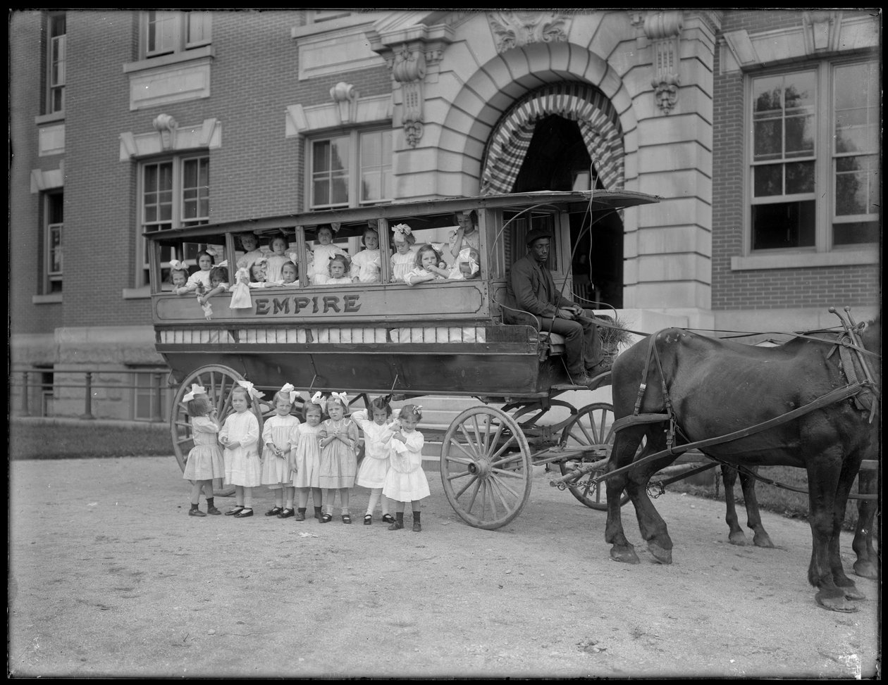 Pienet tytöt poseeraavat hevosvaunussa ja sen edessä, tuntemattoman rakennuksen edessä, luultavasti roomalaiskatolinen orpojen turvapaikka, Kingsbridge, Bronx, n. 1910 tekijältä William Davis Hassler