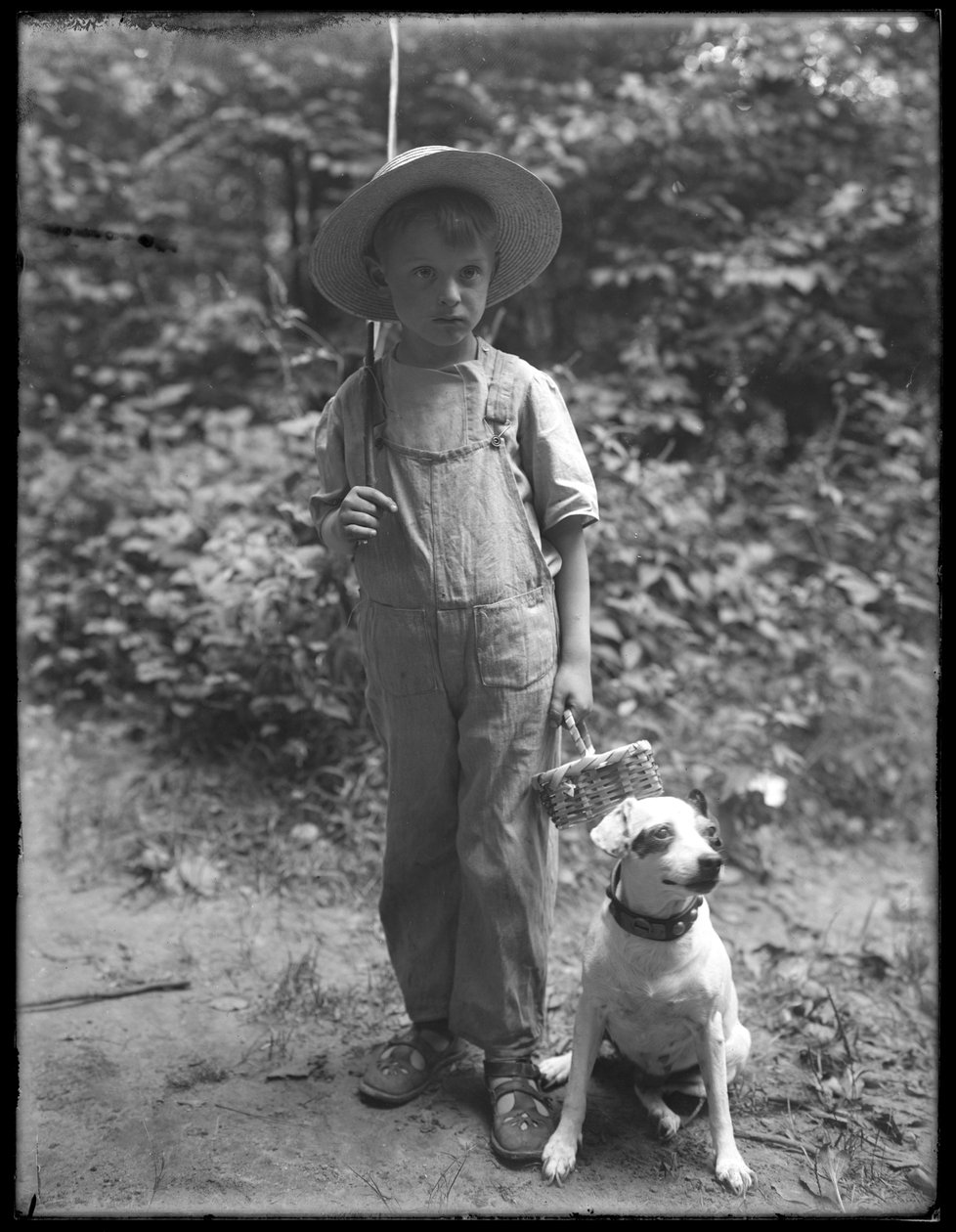 William Gray Hassler, olkihattu ja haalarit, mukanaan onki ja kori, poseeraa metsässä pienen koiran (Bessie) kanssa, 20. elokuuta 1911. tekijältä William Davis Hassler