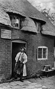 Mies polttaa piippua liikkeen ulkopuolella, Worcestershire, vuodelta 1922.