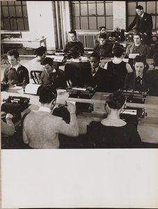 [Ihmiset istuvat kirjoituskoneiden ääressä kuulokkeet päässä]