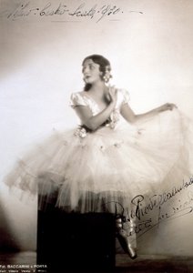 Klassisen balerina Rosa Piovella Ansaldon muotokuva tutuissa ja balettikengissä. Hän istuu edessä, hänen kasvonsa sivuun käännettyinä. Kangasruusut koristavat hänen vaatteensa ja huolellisesti pukeutuneita hiuksiaan (Milano, Teatro alla Scala) (m/v kuva) tekijältä Baccarini and Porta