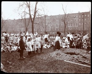 Aikuiset ja lapset pitelevät lippuja seisomassa juuri kaivetun reiän ympärillä puunistutusta varten Arbor Dayna Tompkins Square Parkissa, New Yorkissa, 1904 (hopeagelatiiniprintti)