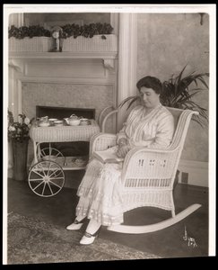 Rouva Howard istuu kirjan kanssa keinutuolissa kotonaan osoitteessa 200, 5th Avenue, New York, 1915-1916 (hopeagelatiiniprintti)