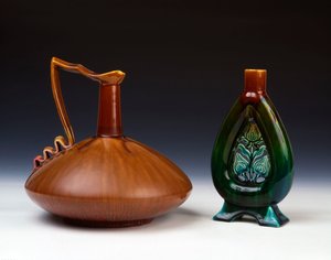 Linthorpe-keramiikka, jossa on puristettu pallomainen muoto, jossa on raidallista karamelli-, vihreää ja karmiininpunaista lasitetta, ja Linthorpe Pottery -maljakko, jossa on lävistetty kukkanuppukoriste ja kirjava vihreä, sininen ja ruskea lasite tekijältä Christopher Dresser