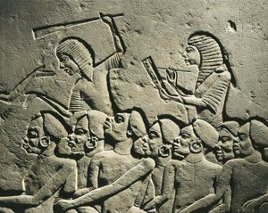 Joukko negroideja vankeja, joita nuijilla aseistetut vartijat ympäröivät, kun kirjuri laatii raporttia. Reliefi Horemhebin haudasta Saqqarassa, yksityiskohtia tekijältä Egyptian 18th Dynasty