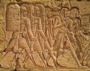 Uuden kuningaskunnan Ramses III:n ruumistemppelin (n. 1184–1153 eKr.) kohokuvio, joka kuvaa köyttä ja aseita kantavia palvelijoita