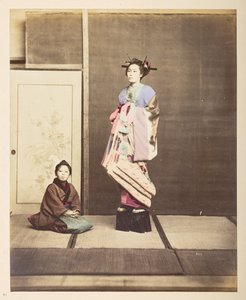 [?Geisha, ] Täyspitkä seisova studiomuotokuva nuoresta naisesta korotetuissa kengissä, hänen nuori palvelijansa polvistumassa lattialla hänen vieressään,   Valokuvaaja: Tuntematon  Lucas Collection: Valokuvaennätys Charles Jamesin ja Morton P, Luc tekijältä English Photographer
