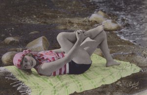 Tyttö makaa pyyhkeellä rannalla (värillinen kuva) tekijältä English Photographer
